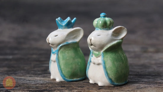 Cute clay rabbit figurines wearing green cloaks and blue crowns, perfect for crafting decor.
