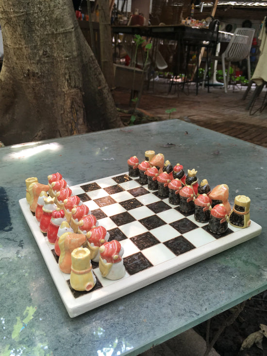 Handcrafted clay chess set with cute animal pieces on outdoor table
