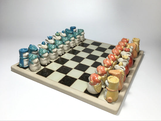 Cute clay chess set with animal figurines in blue and orange tones on checkered board